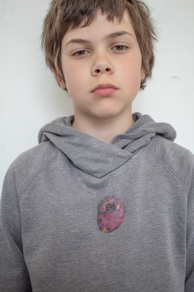 Young boy with grey sweater, brooch attached to sweater