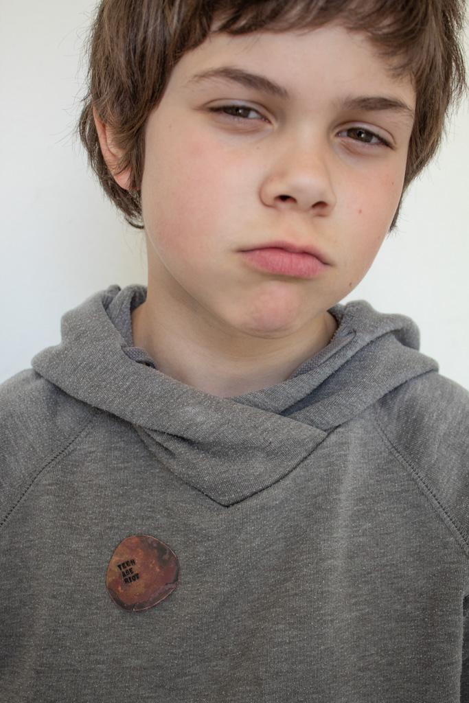 Young boy with grey sweater, brooch attached to sweater